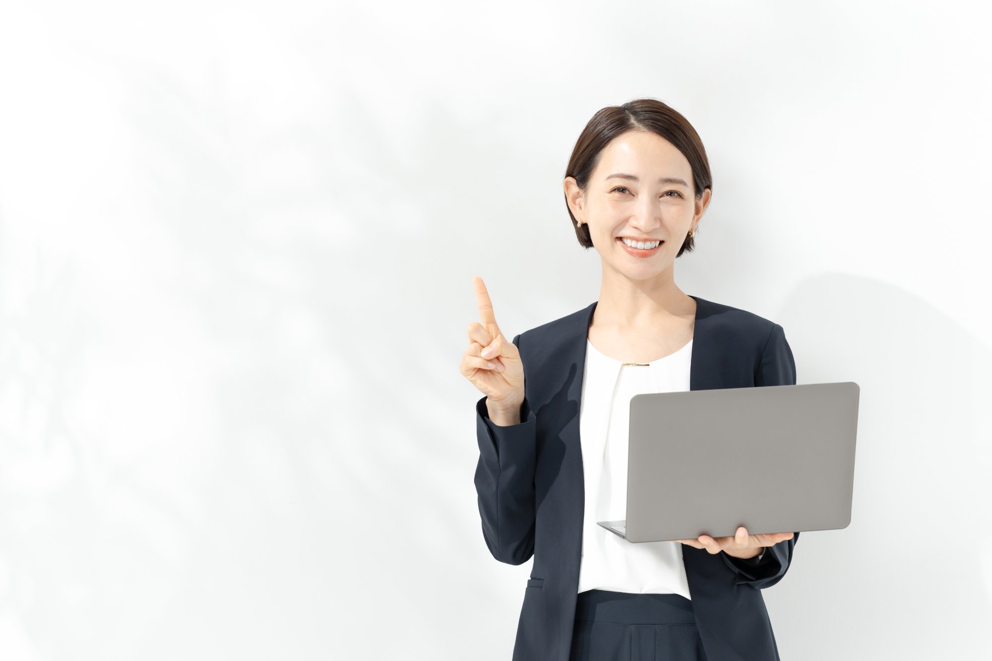 ノートPCを持ちポイントを示すビジネス担当者