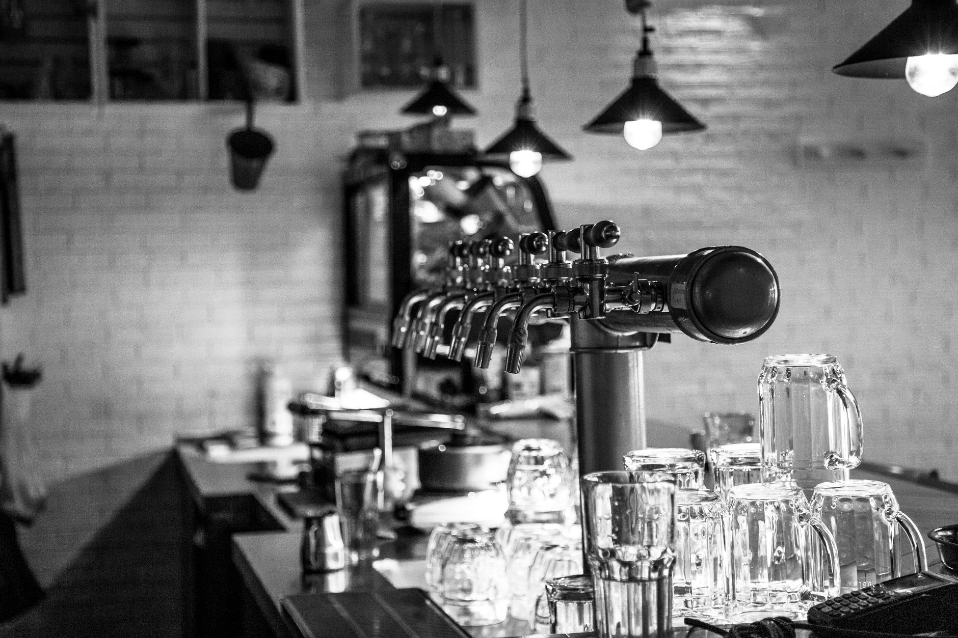 Monochrome image of a bar counter with beer taps and glasswa