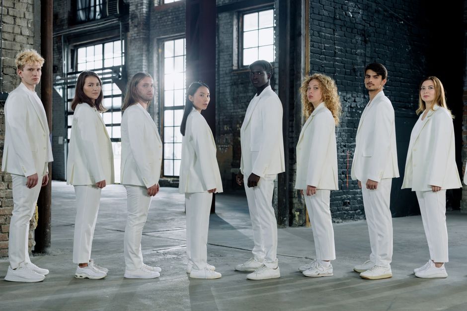 Diverse group of young adults in white suits standing in an