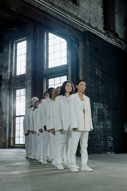 Diverse group in white suits stands aligned in an industrial
