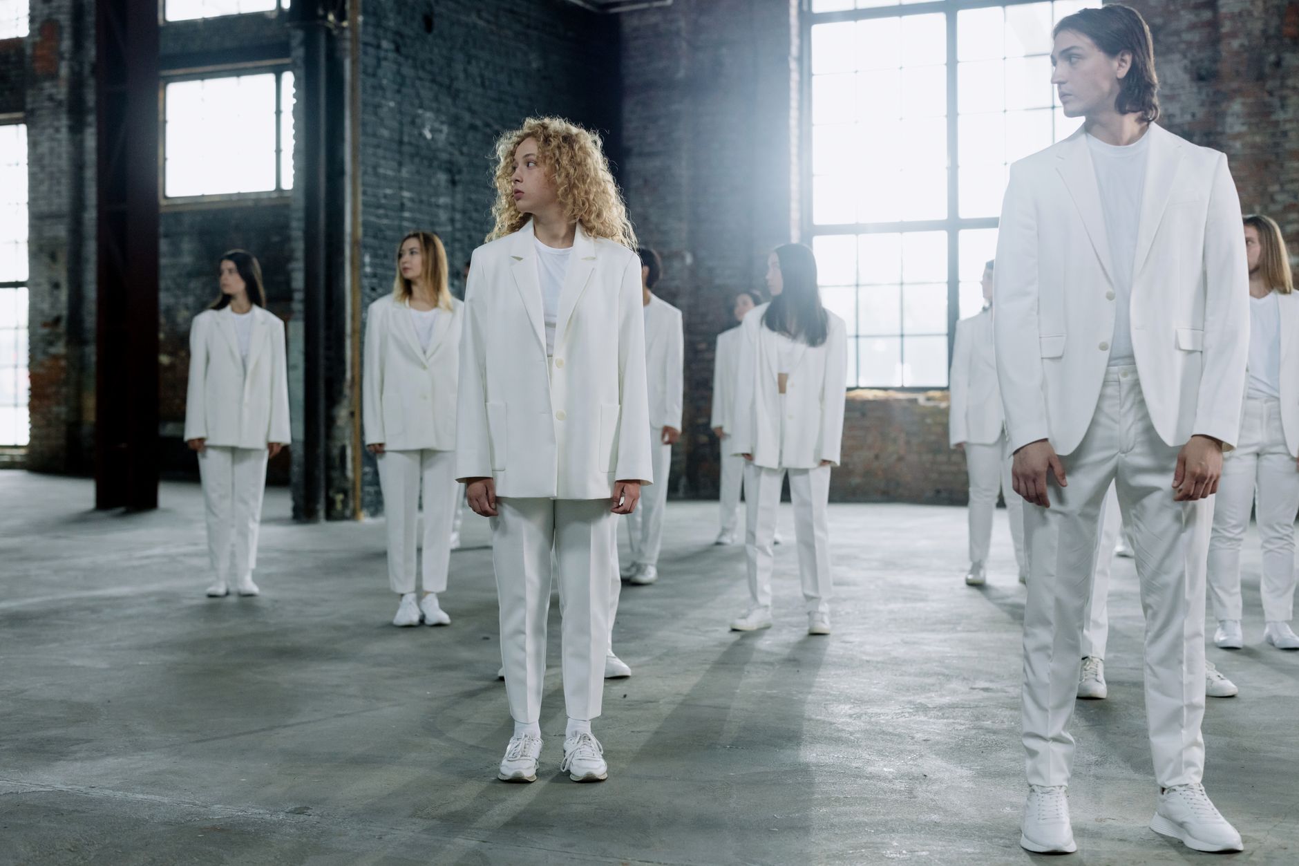 A diverse group of adults in white suits stands inside a lar