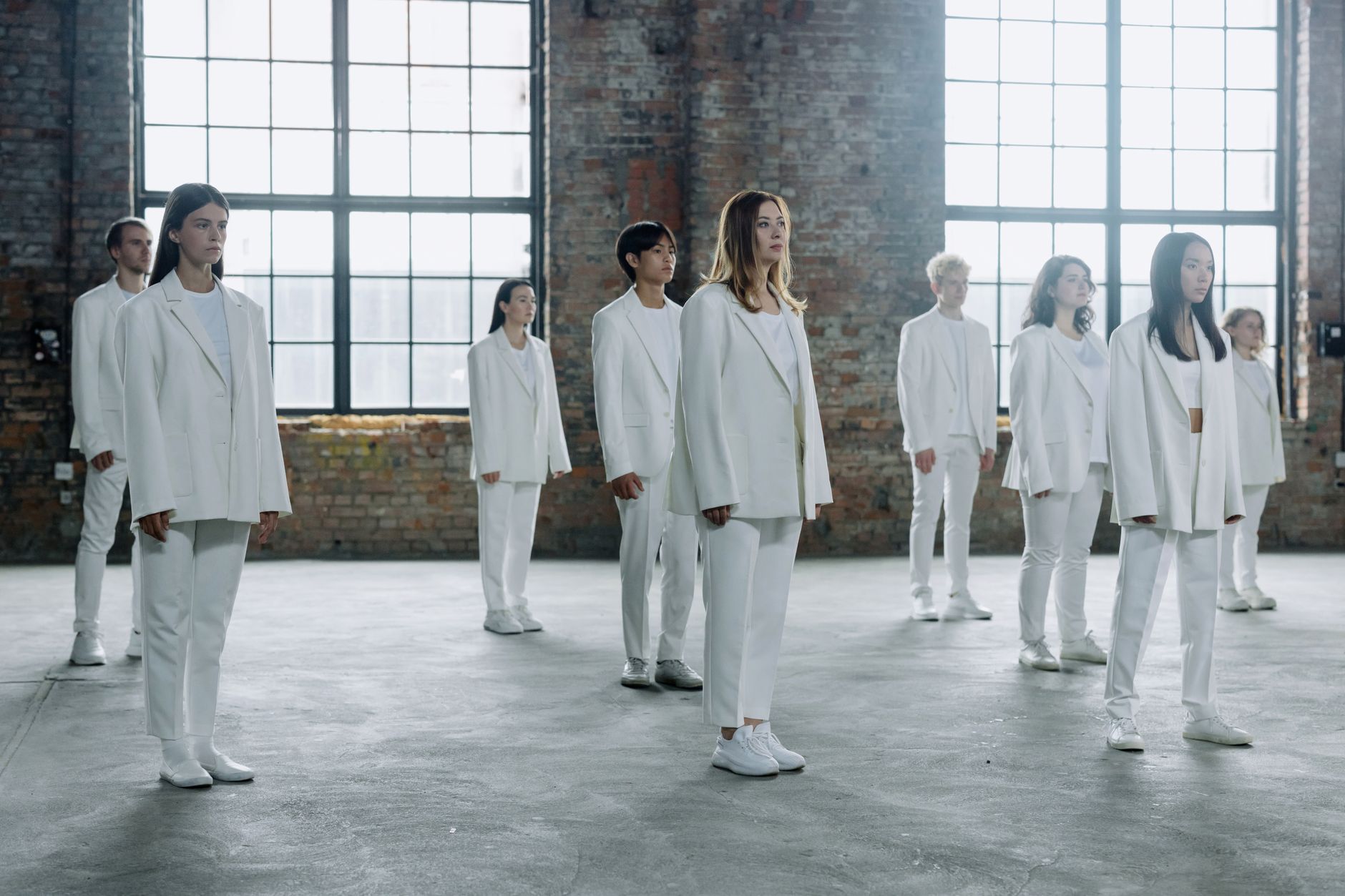 A group of diverse individuals in white outfits standing ser