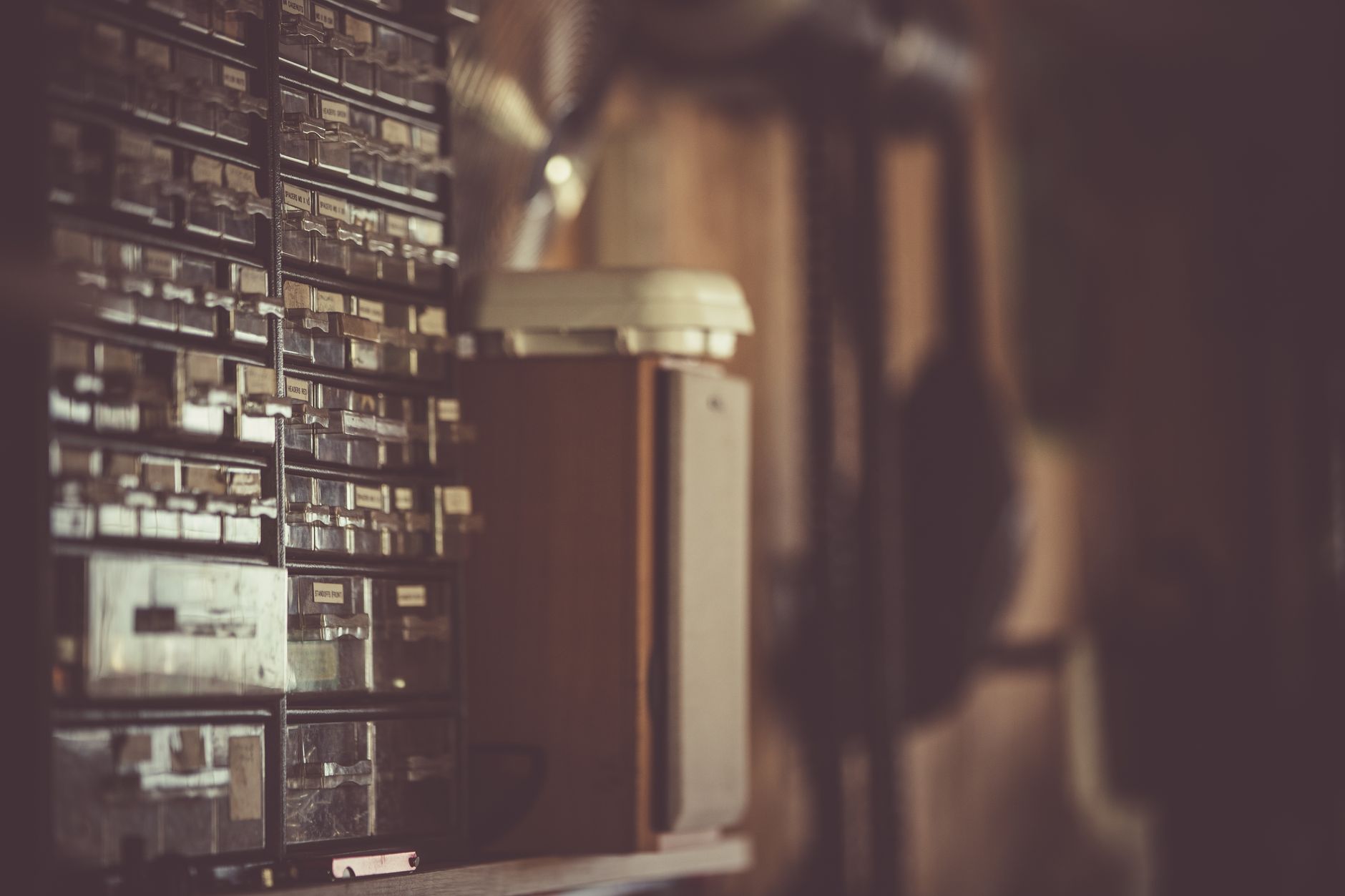 Vintage storage cabinet with labeled drawers in a dimly lit room, creating a nostalgic atmosphere.