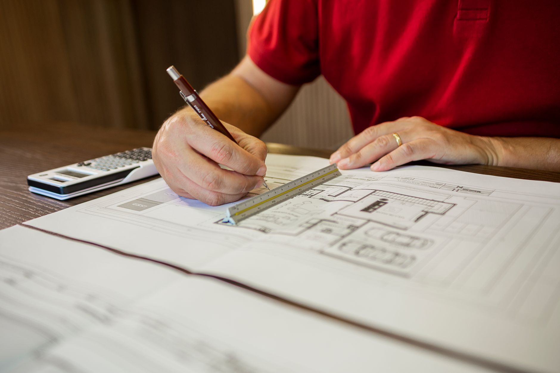 Architect working on floor plans with ruler and pencil in an