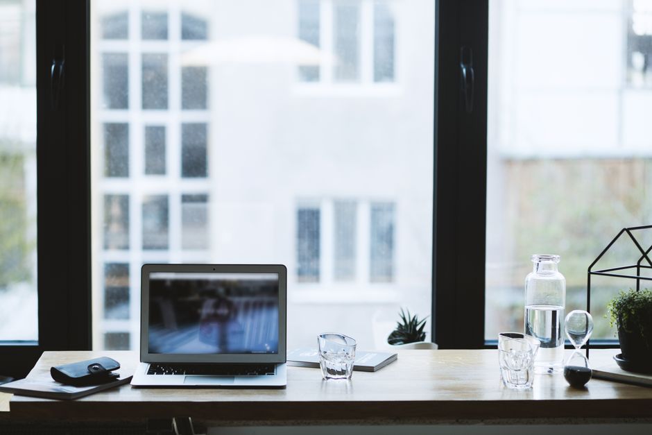 Sleek office desk setup featuring a laptop, glass of water,