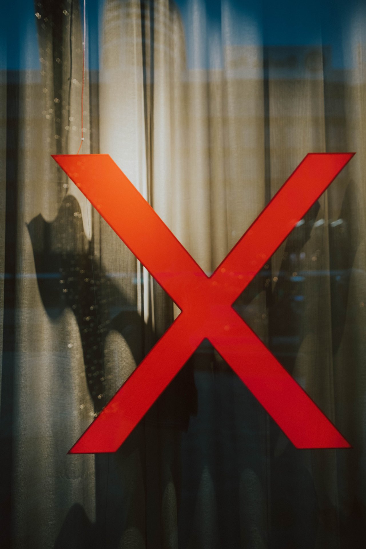 A striking red X on a glass window with intriguing shadows b