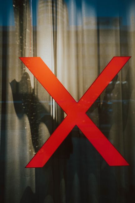 A striking red X on a glass window with intriguing shadows b