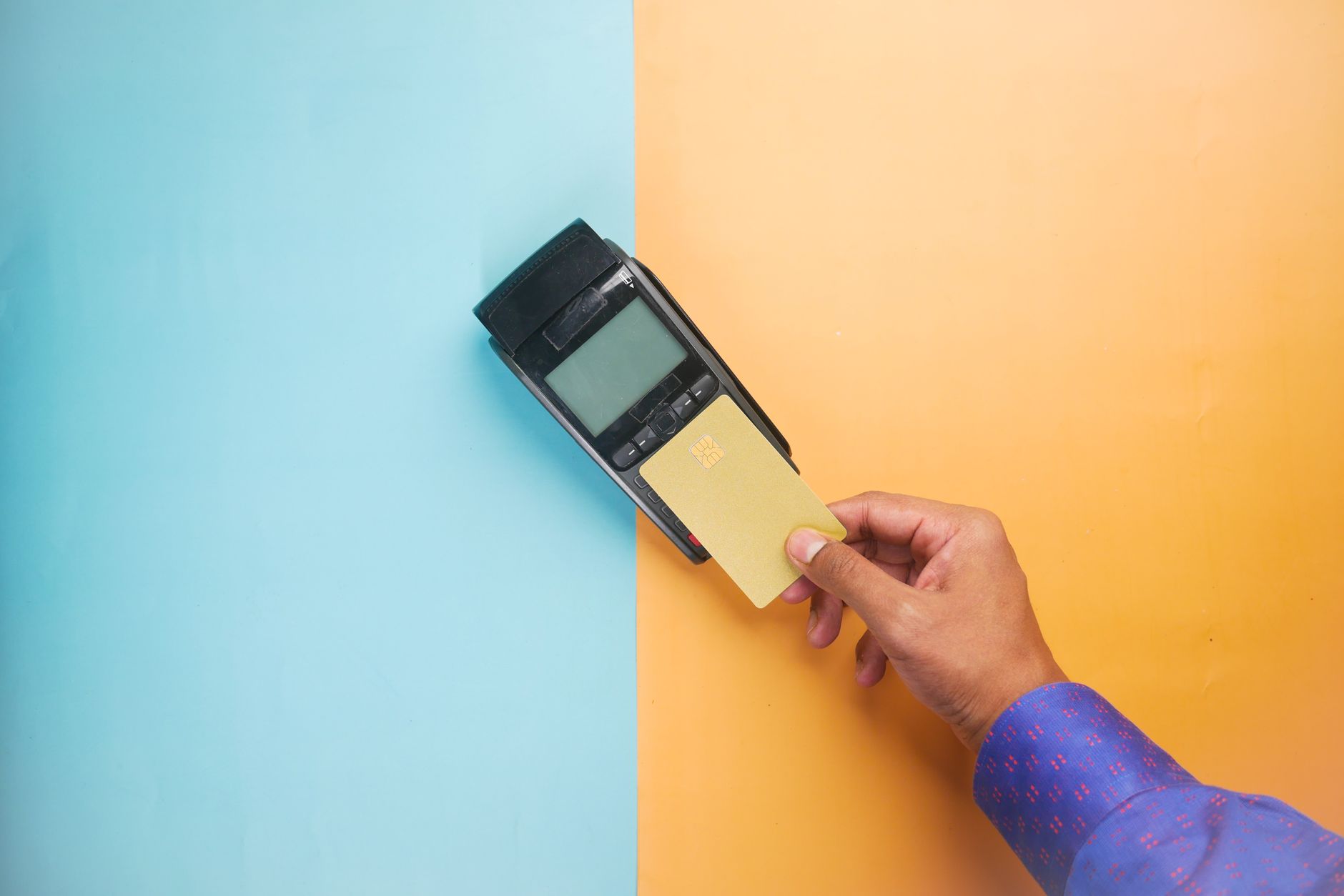 A hand tapping a credit card on a payment terminal for a con