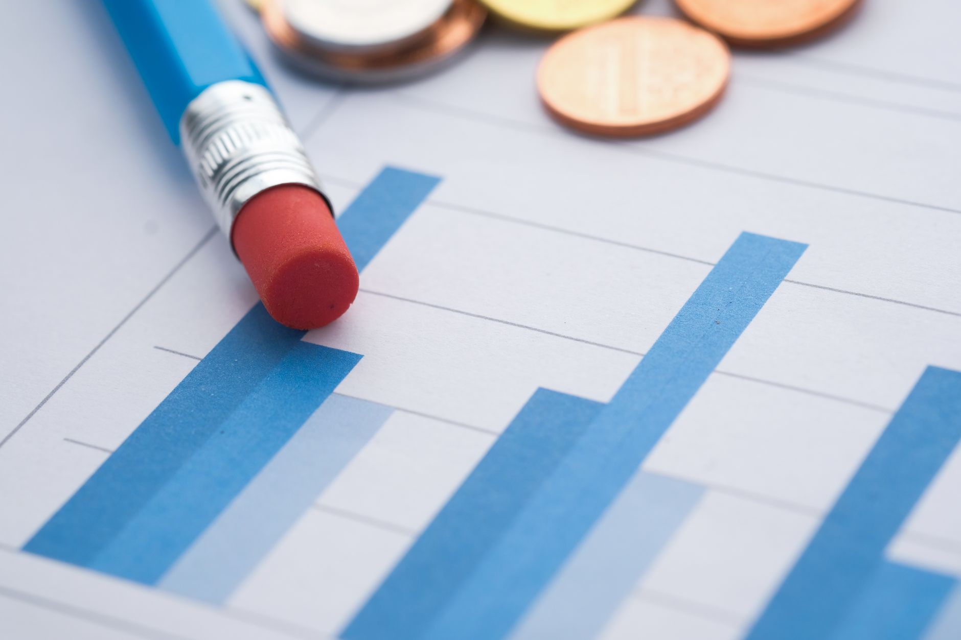 Close-up of bar graphs with a pencil and coins, symbolizing