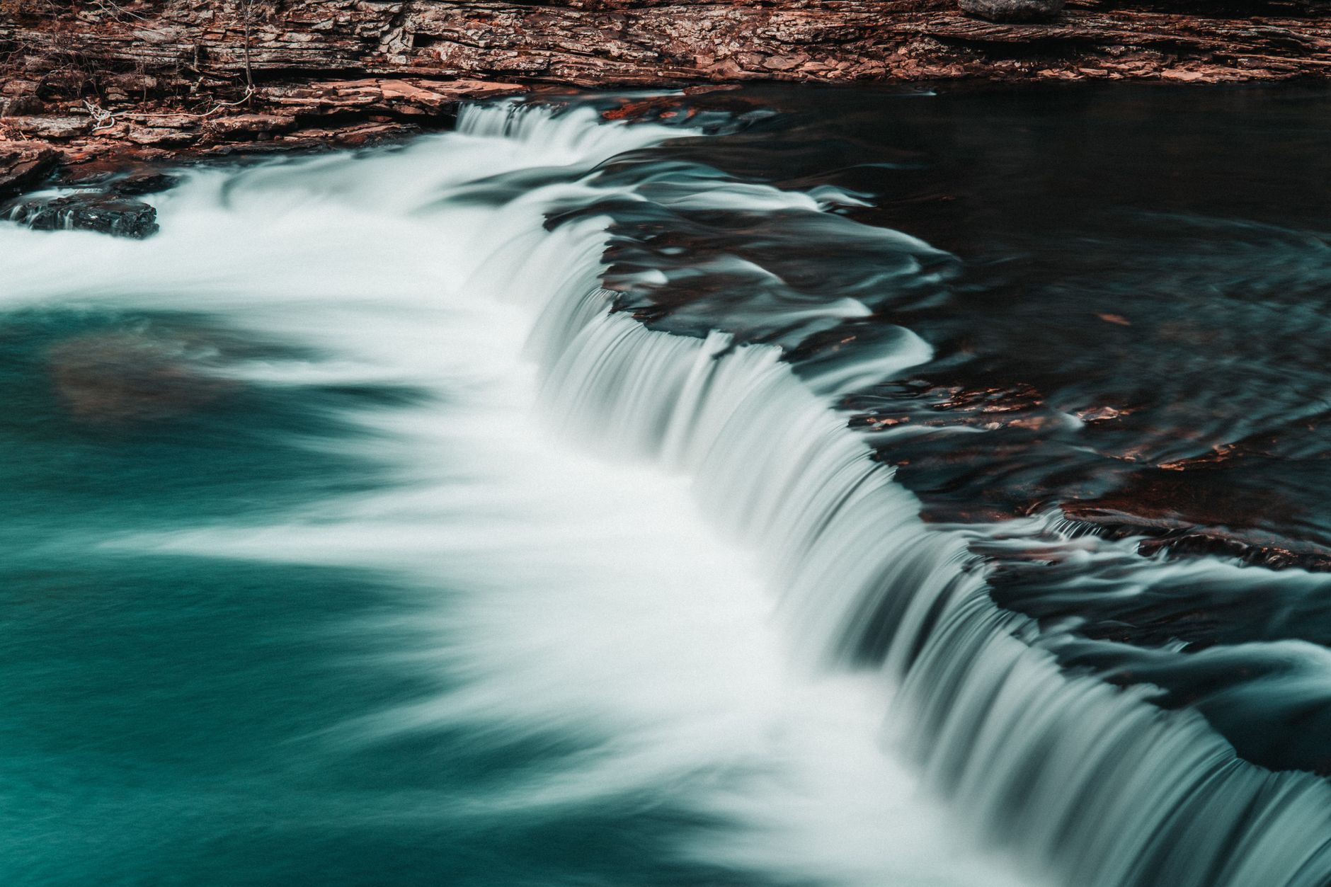 A tranquil cascade waterfall flowing over smooth rocks, capt
