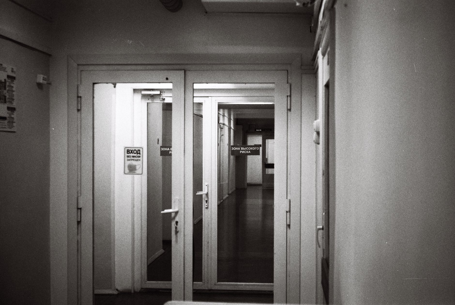 Empty hospital corridor in black and white, emphasizing open doors and healthcare environment.