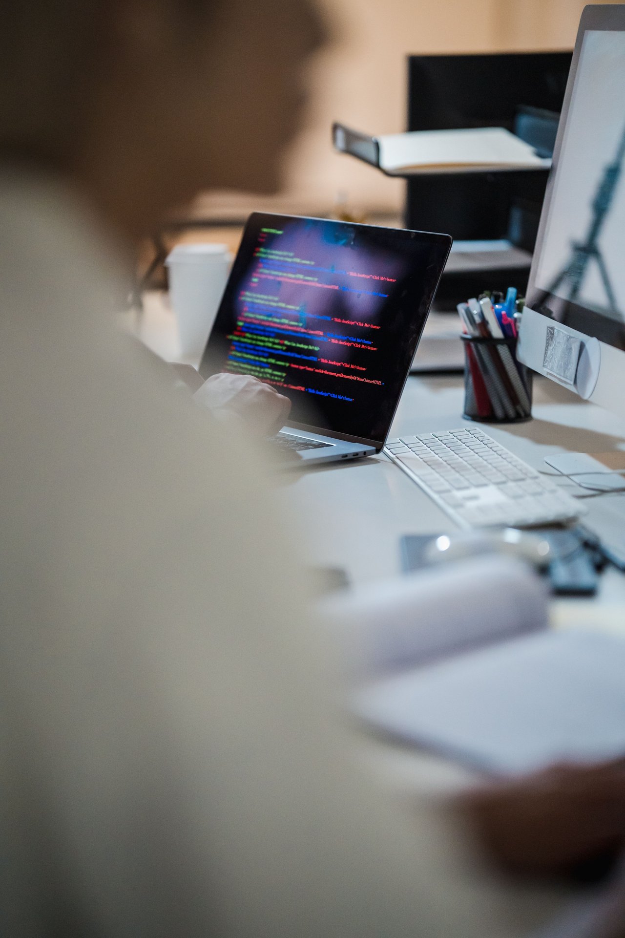 Blurred figure at a desk with a laptop displaying colorful c