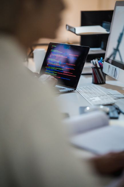 Blurred figure at a desk with a laptop displaying colorful c