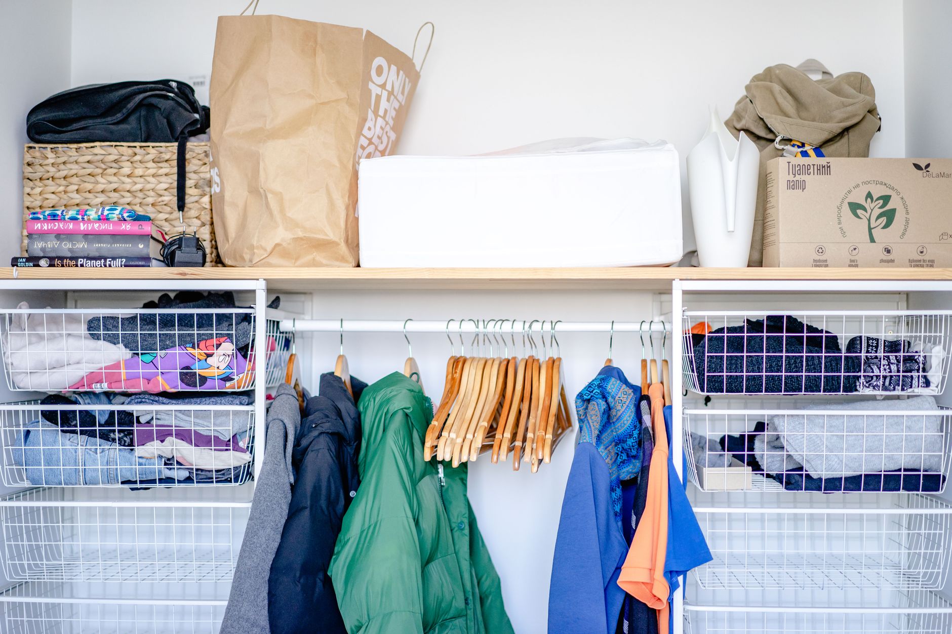 A minimalist open wardrobe featuring modern clothing, hangers, and storage baskets.