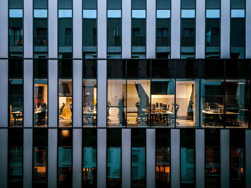 Illuminated office inside a modern glass building exterior,