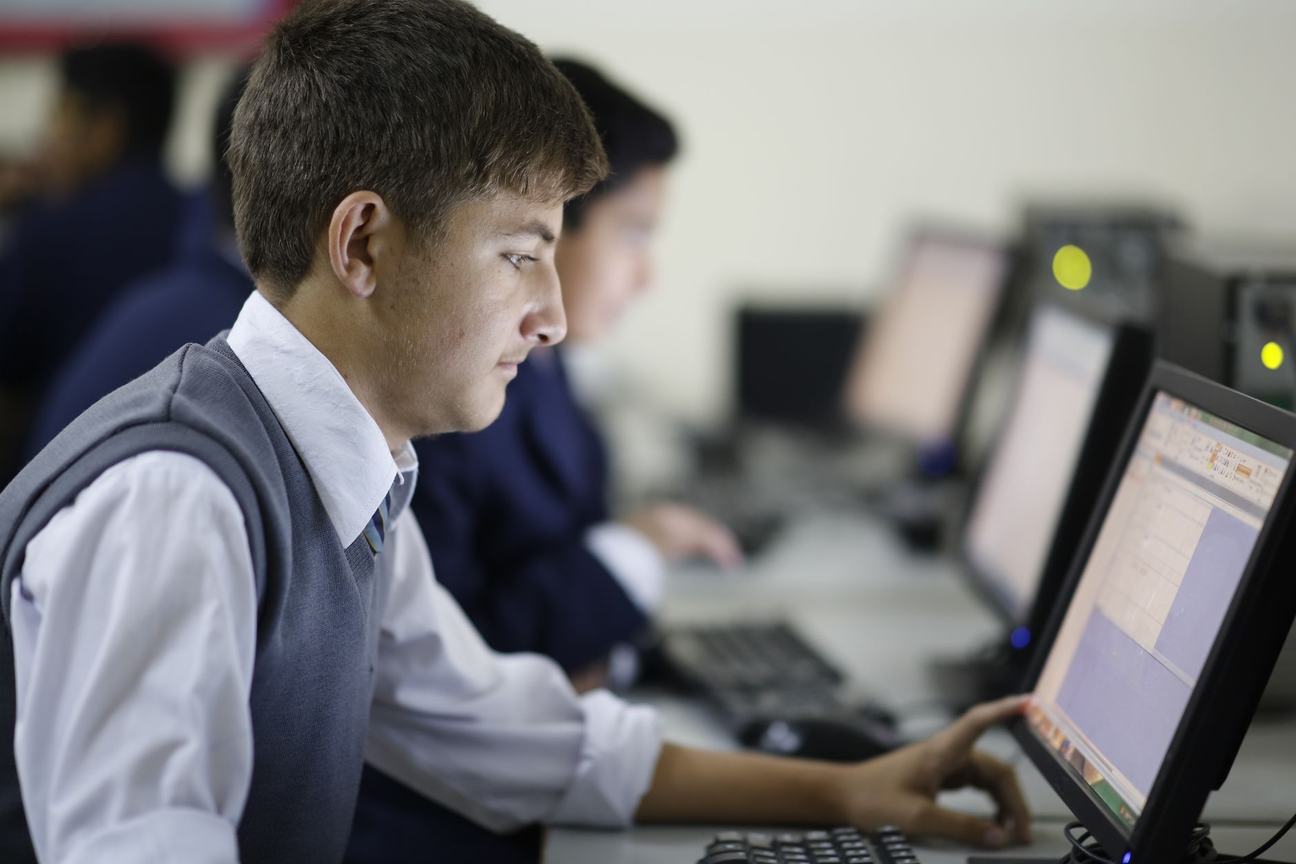 Teenage student concentrating in computer lab using a deskto