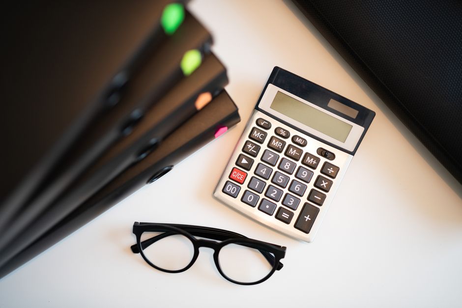 Calculator with glasses and folders on an office desk. Perfe
