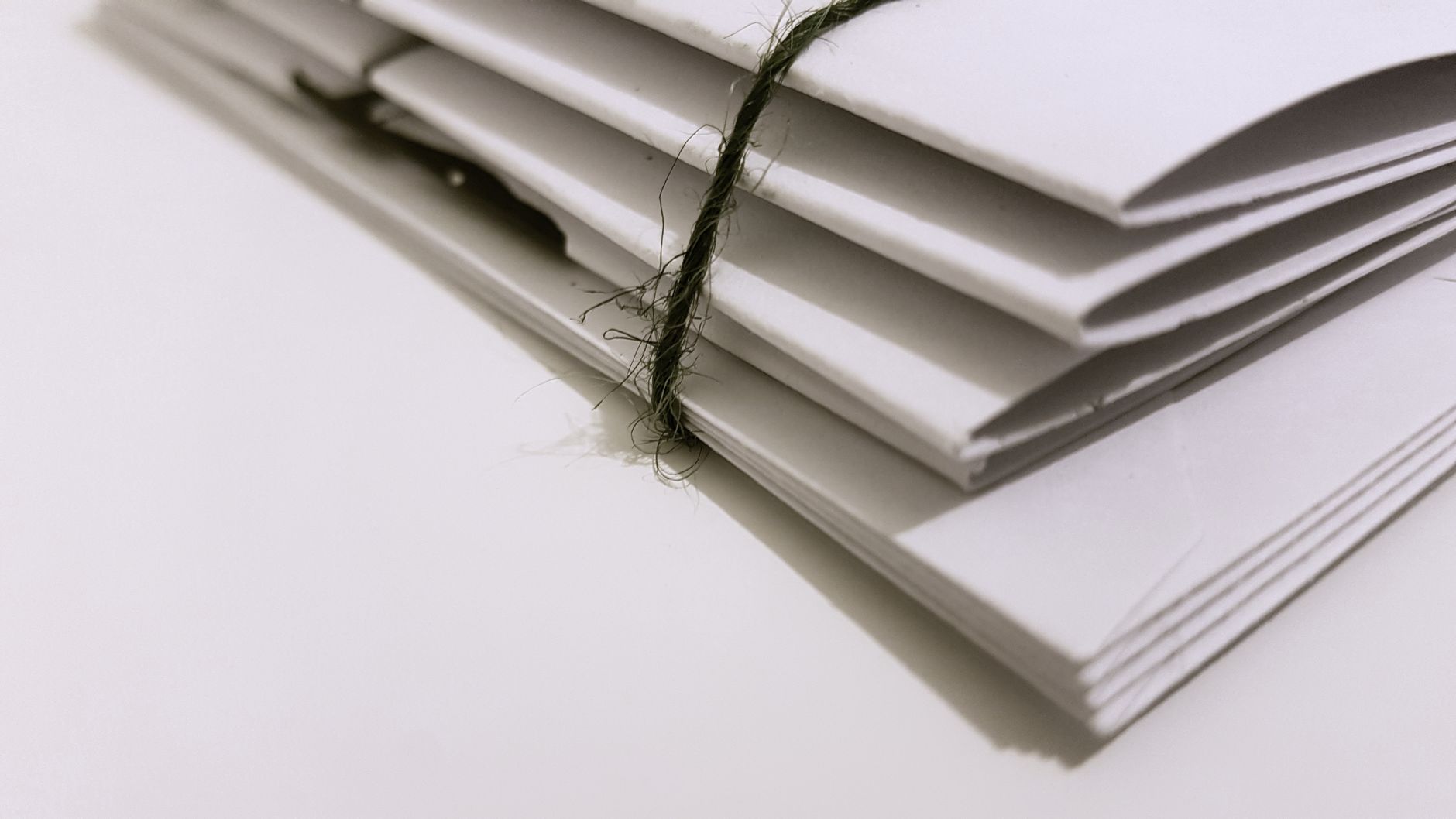Pile of white envelopes tied with a green string, showcasing
