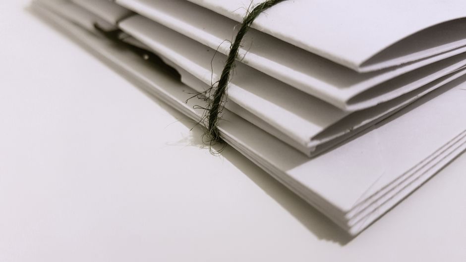 Pile of white envelopes tied with a green string, showcasing