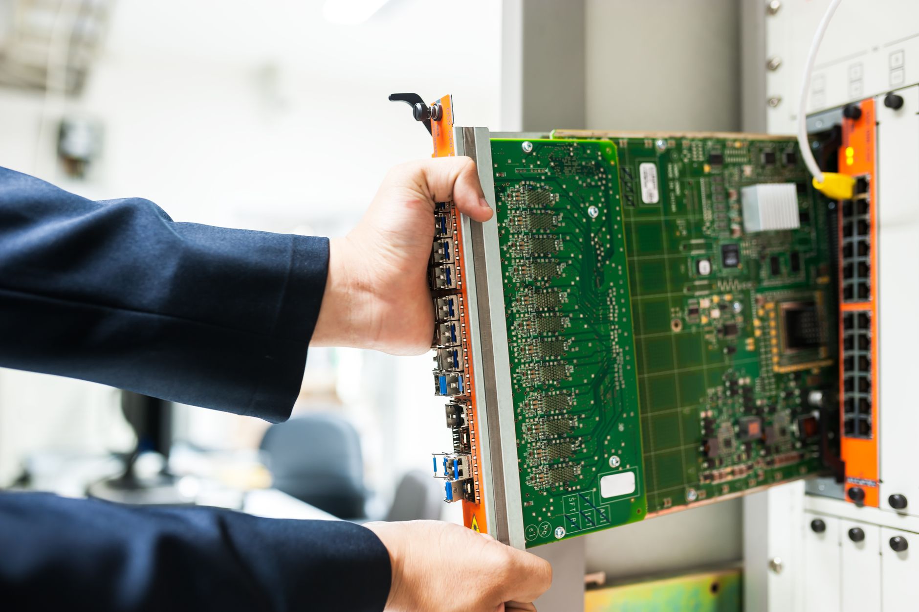 A technician inserts a circuit board into a server rack, ill