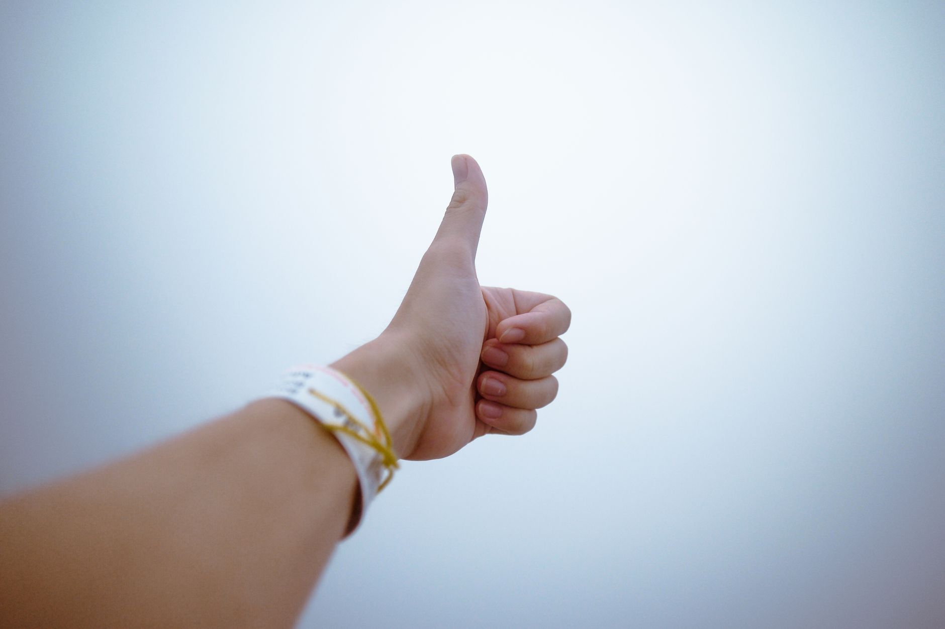 A hand giving a thumbs up gesture symbolizes approval and po