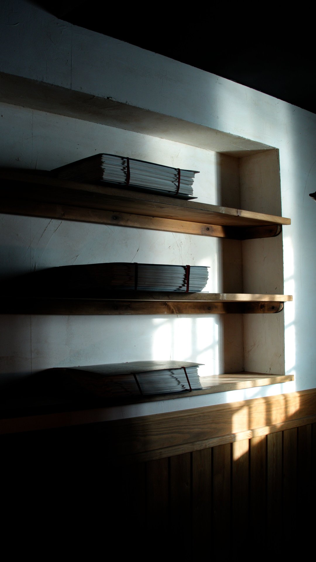 Moody shelves with neatly stacked papers in a shadowy room,