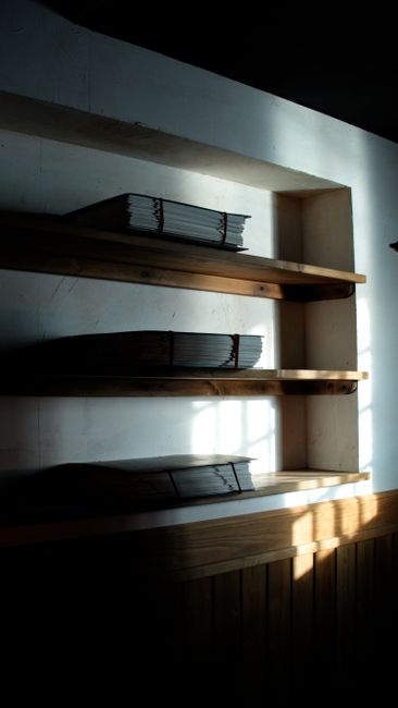 Moody shelves with neatly stacked papers in a shadowy room,