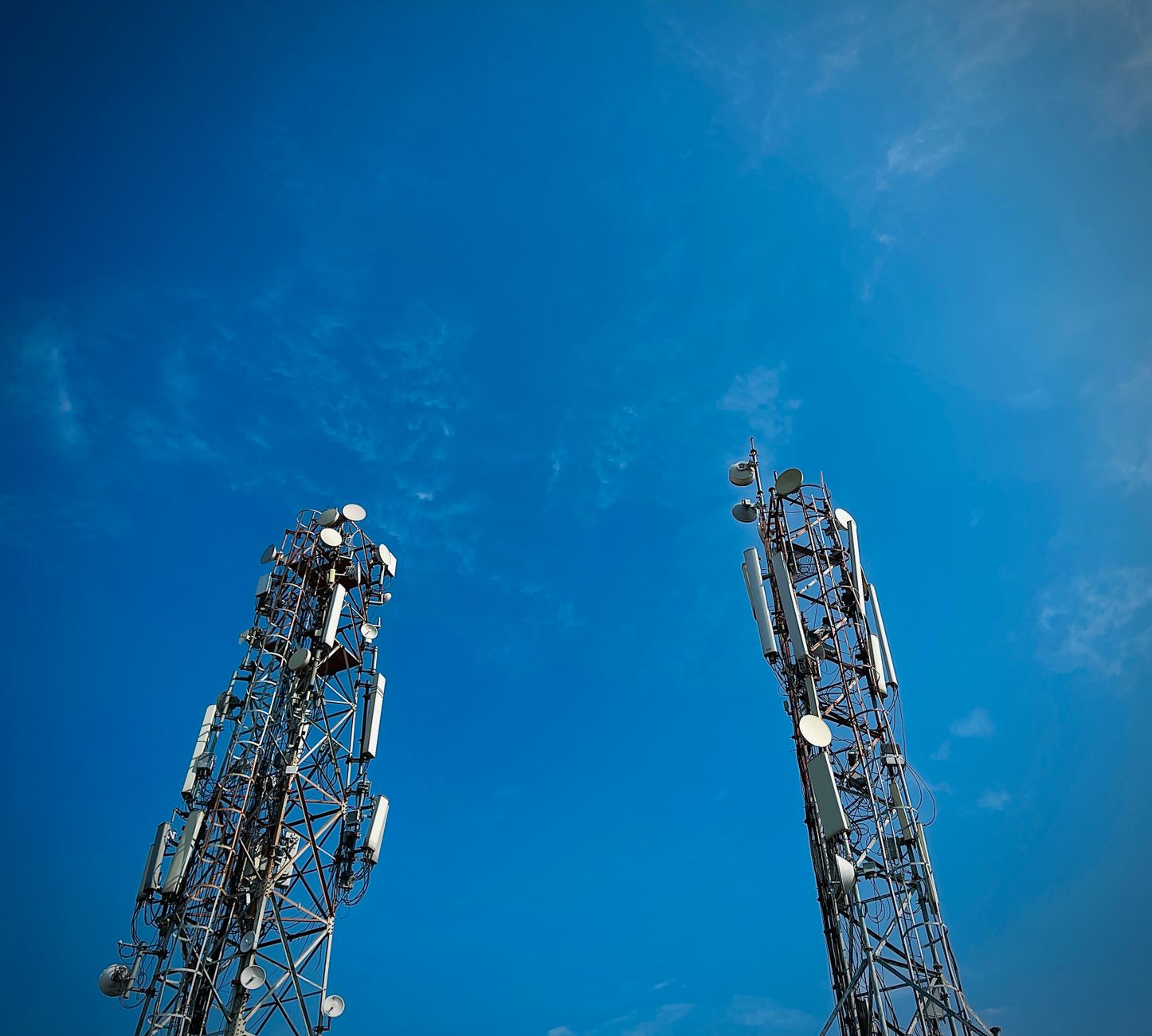 Two telecommunication towers standing against a vibrant clea