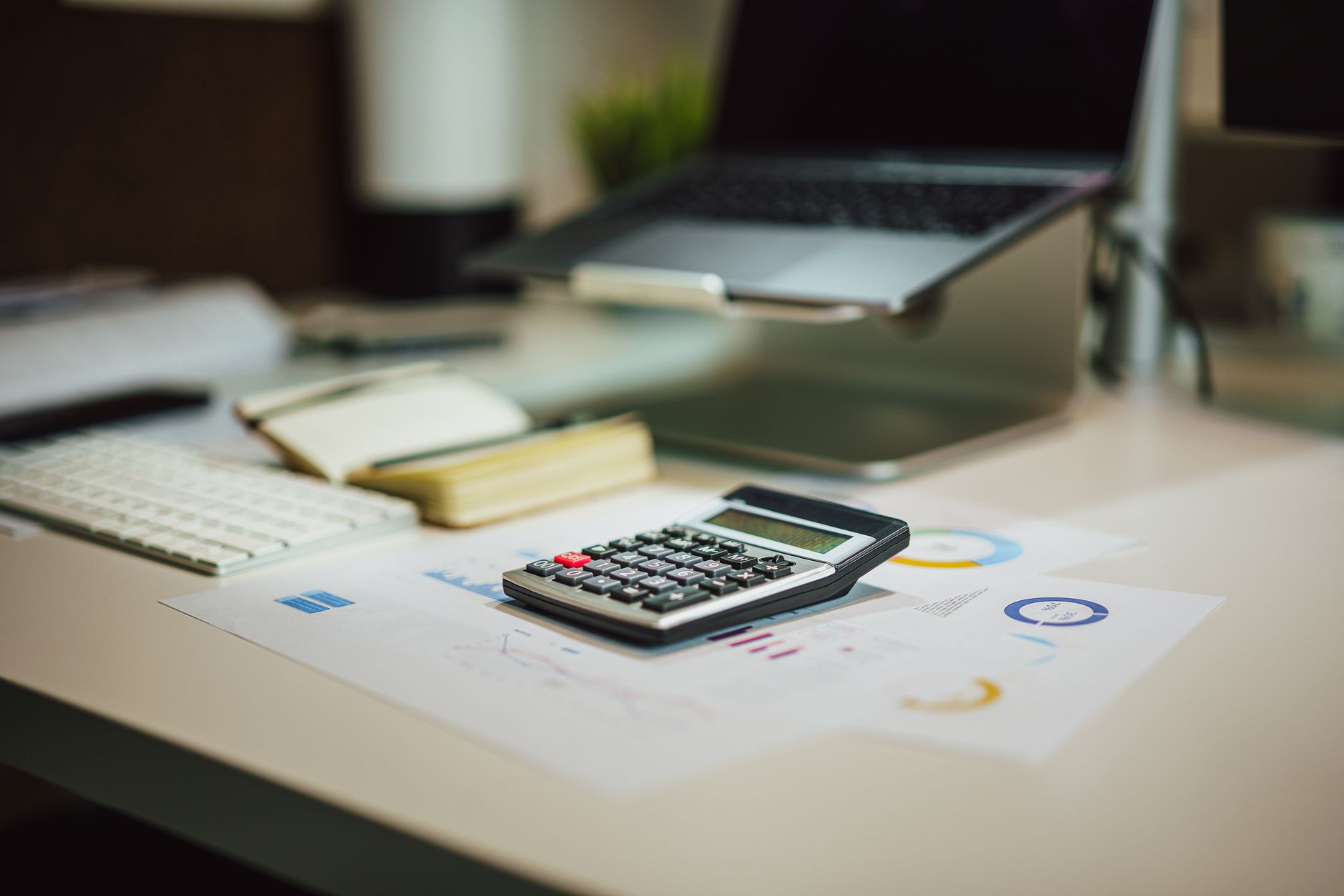 A modern workspace with a laptop, calculator, and documents