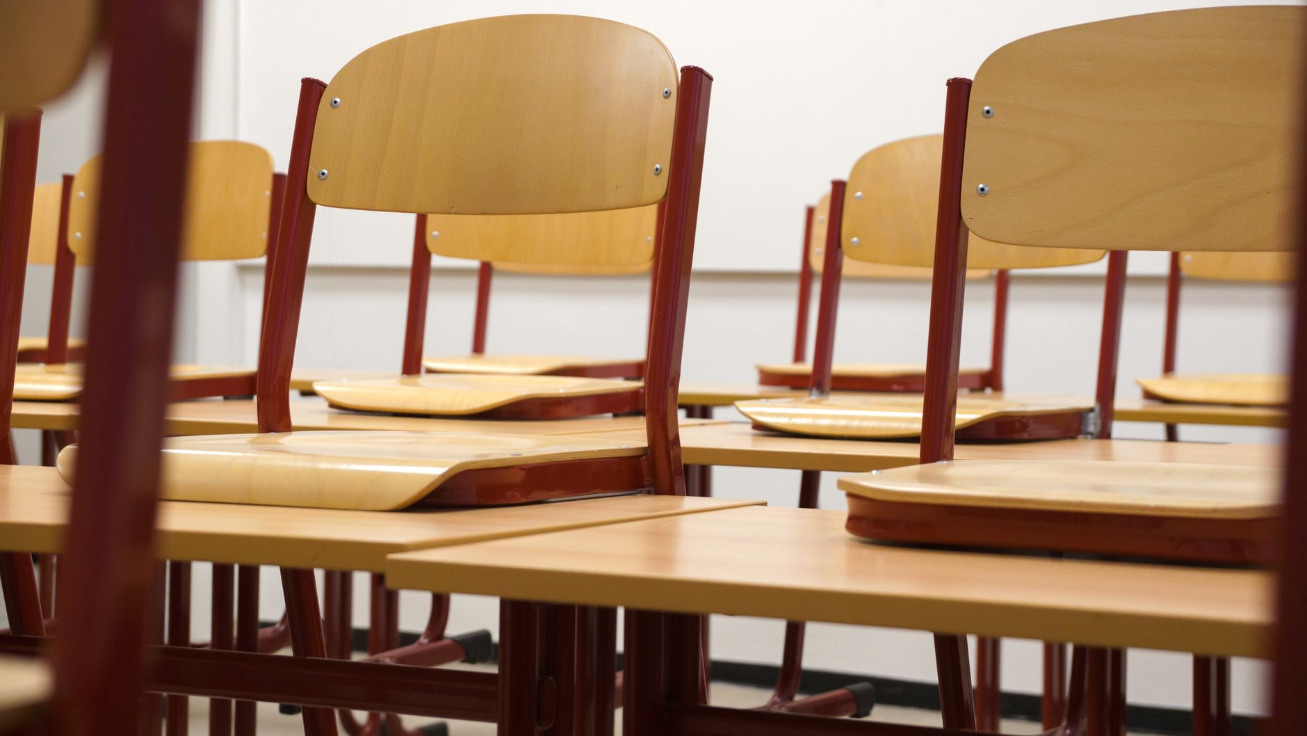 A modern and empty classroom featuring wooden chairs and des