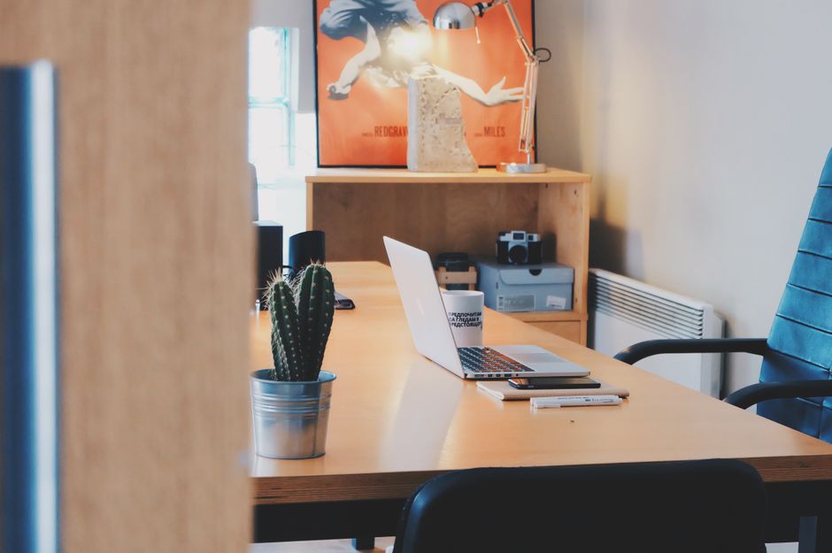 A modern office desk setup featuring a cactus plant, laptop,