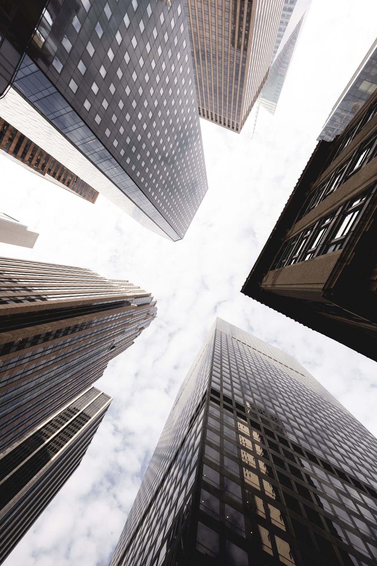 Low-angle shot of New York City's towering skyscrapers piercing a cloudy sky.