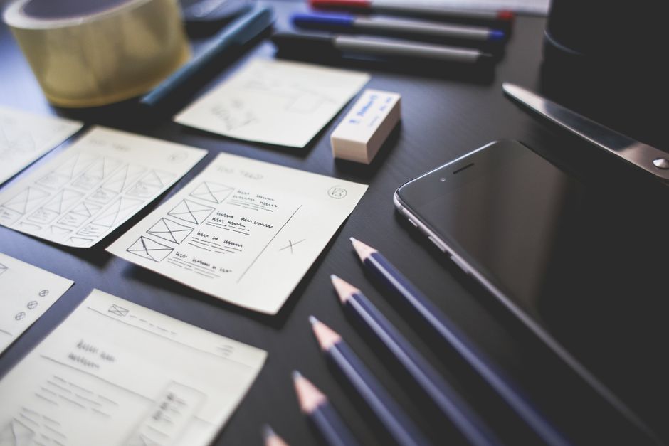 A creative workspace featuring UI design plans, pencils, a s