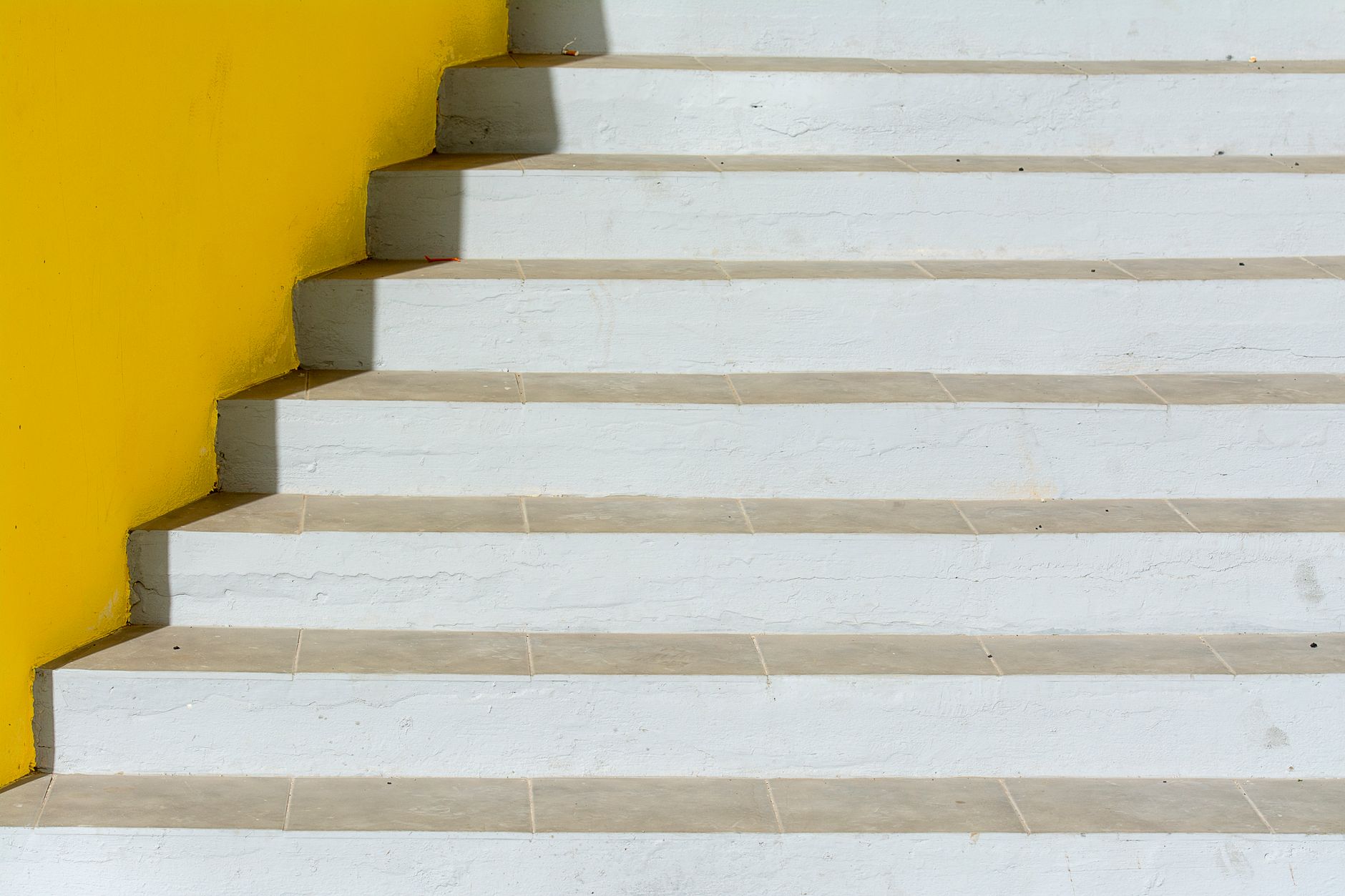A minimalist staircase with white steps and a vibrant yellow