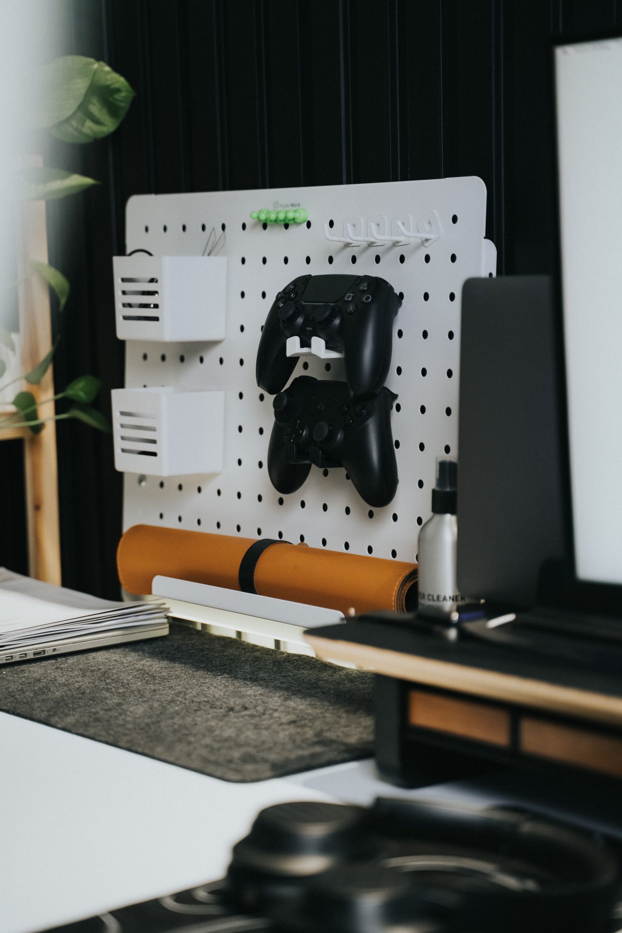 A stylish home office desk with a gaming controller on a pegboard, blending work and play.