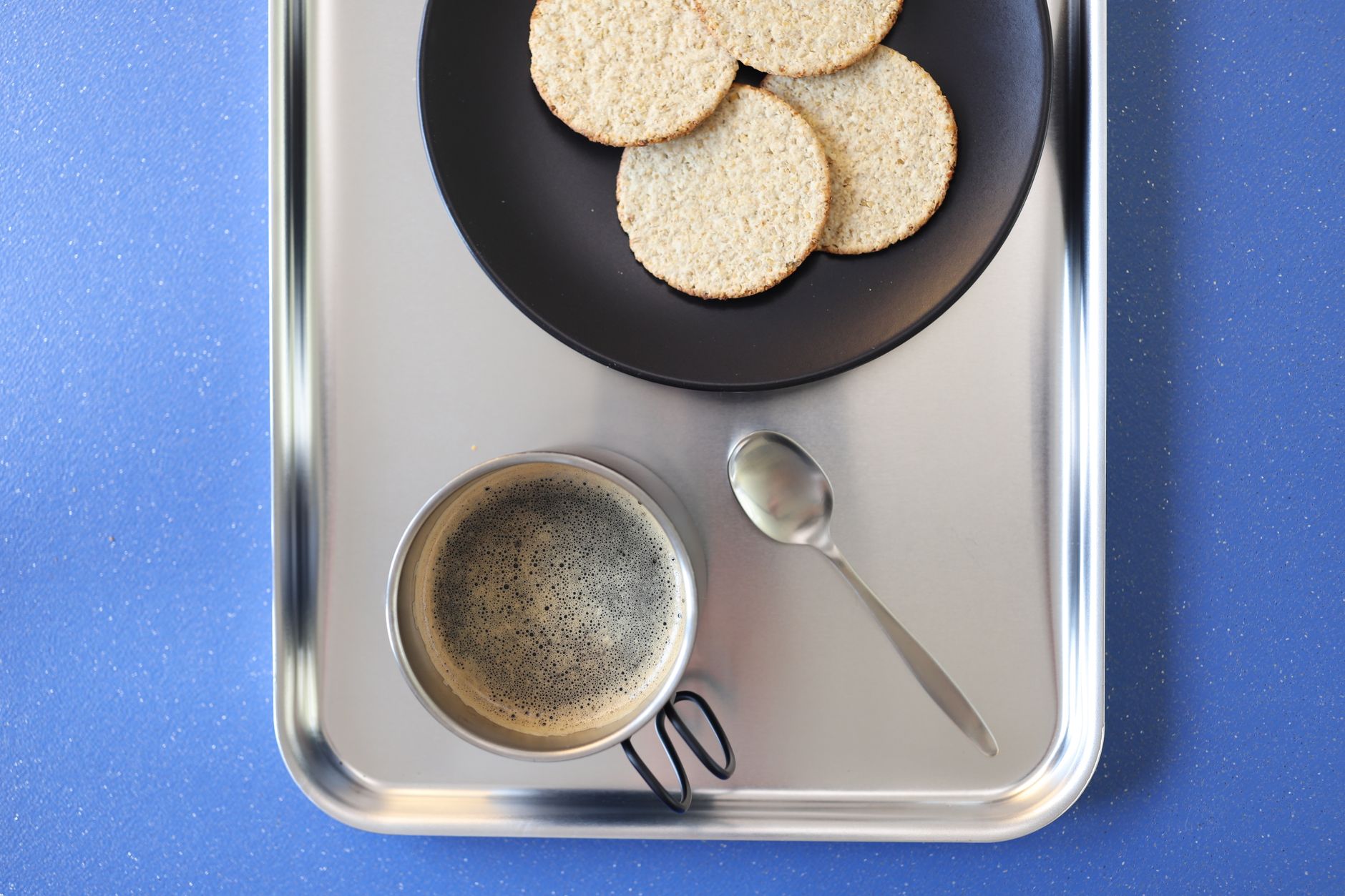 Top view of a cup of coffee with cookies on a tray over a bl