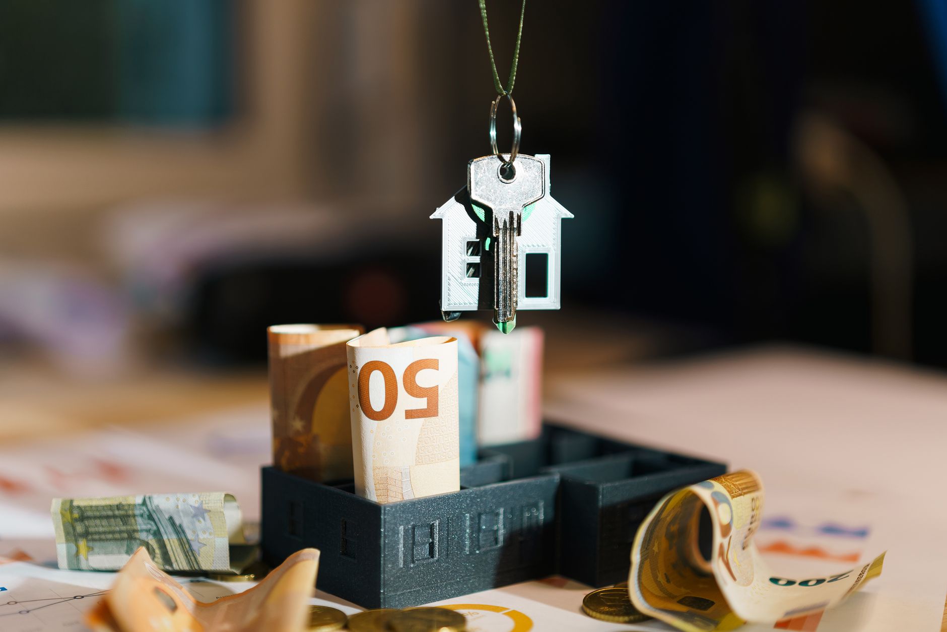 House key over Euro banknotes symbolizes real estate investm