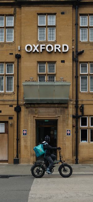 Biker passing in front of Oxford building with classic archi