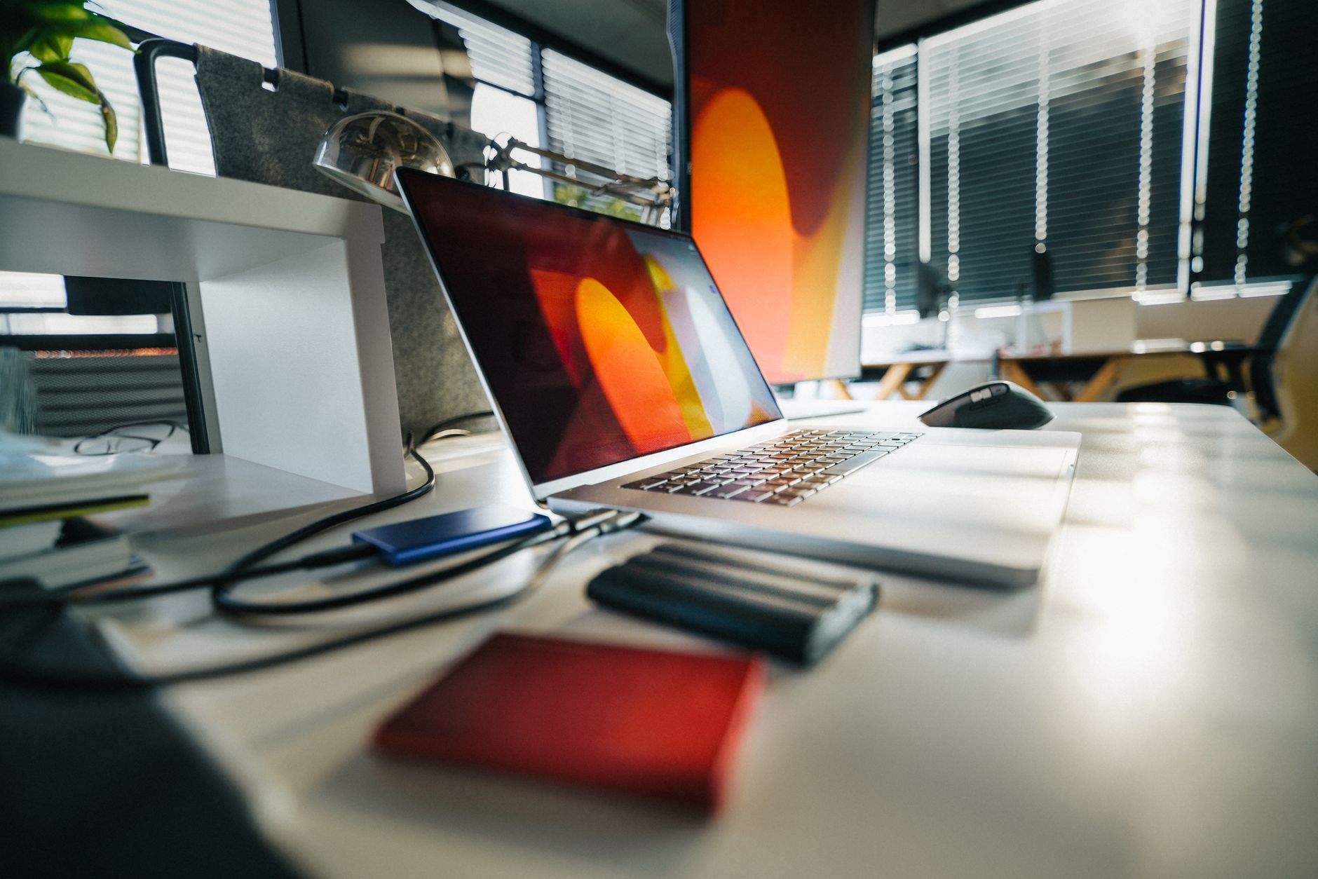 A modern workspace featuring a laptop, external drives, and