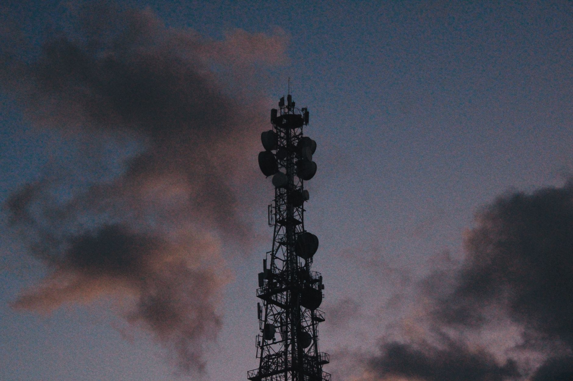 Silhouette of a telecommunications tower against a vibrant t
