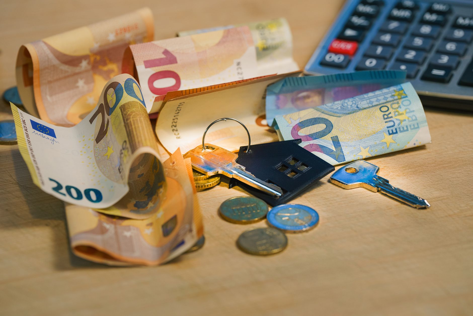 Euro banknotes and coins with house keys on a table symboliz