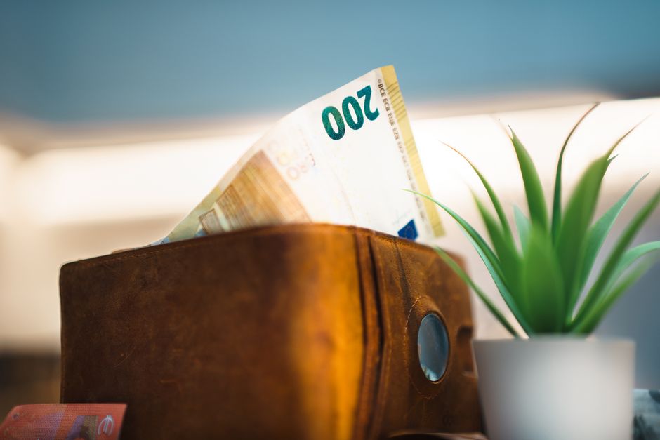 Close-up of a leather wallet holding euro banknotes next to