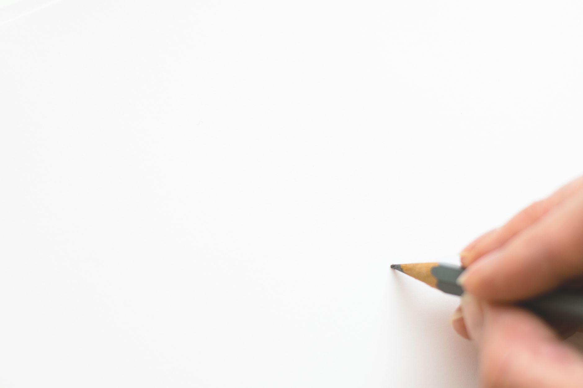 Close-up of a hand sketching on white paper with a pencil, e