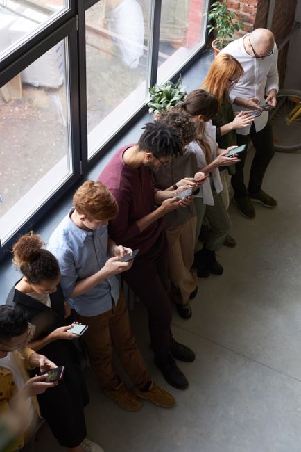 A group of diverse office workers standing by a window using