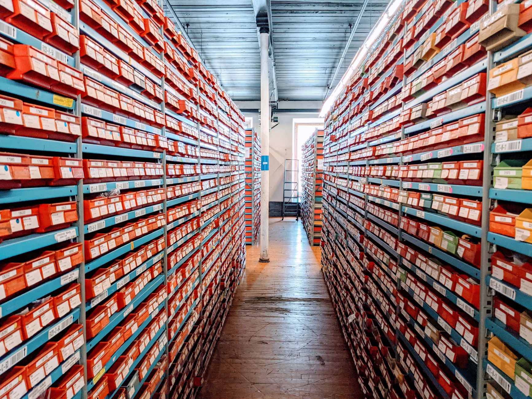 A well-organized warehouse aisle filled with red shoe boxes