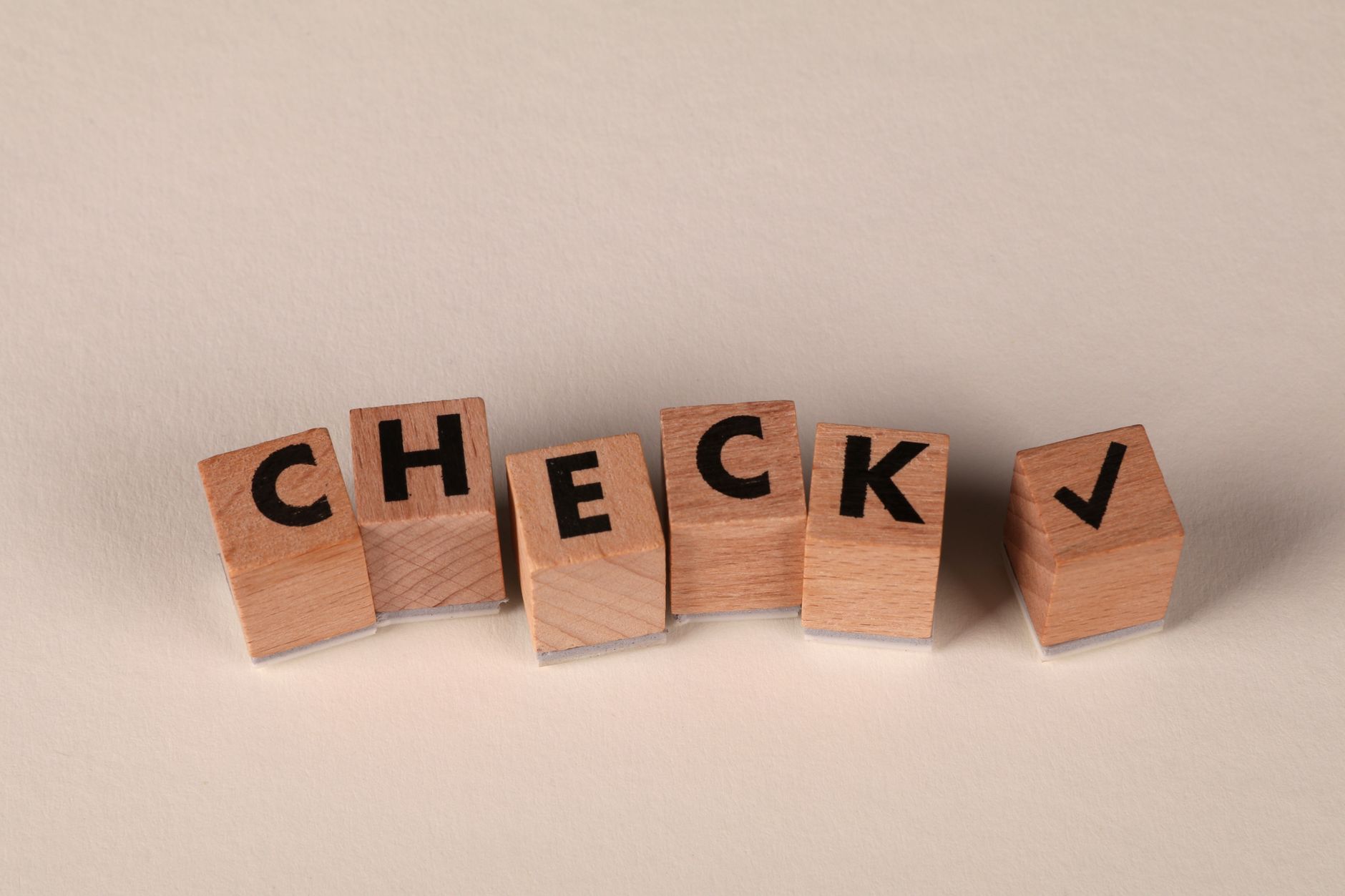 Wooden blocks aligned to spell 'CHECK' with a checkmark symb