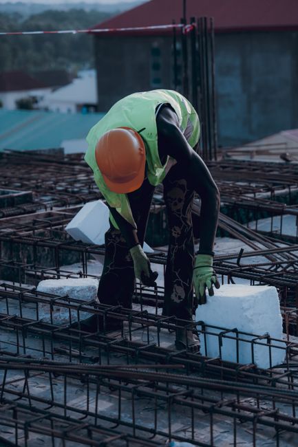 Construction worker with safety gear placing concrete block.