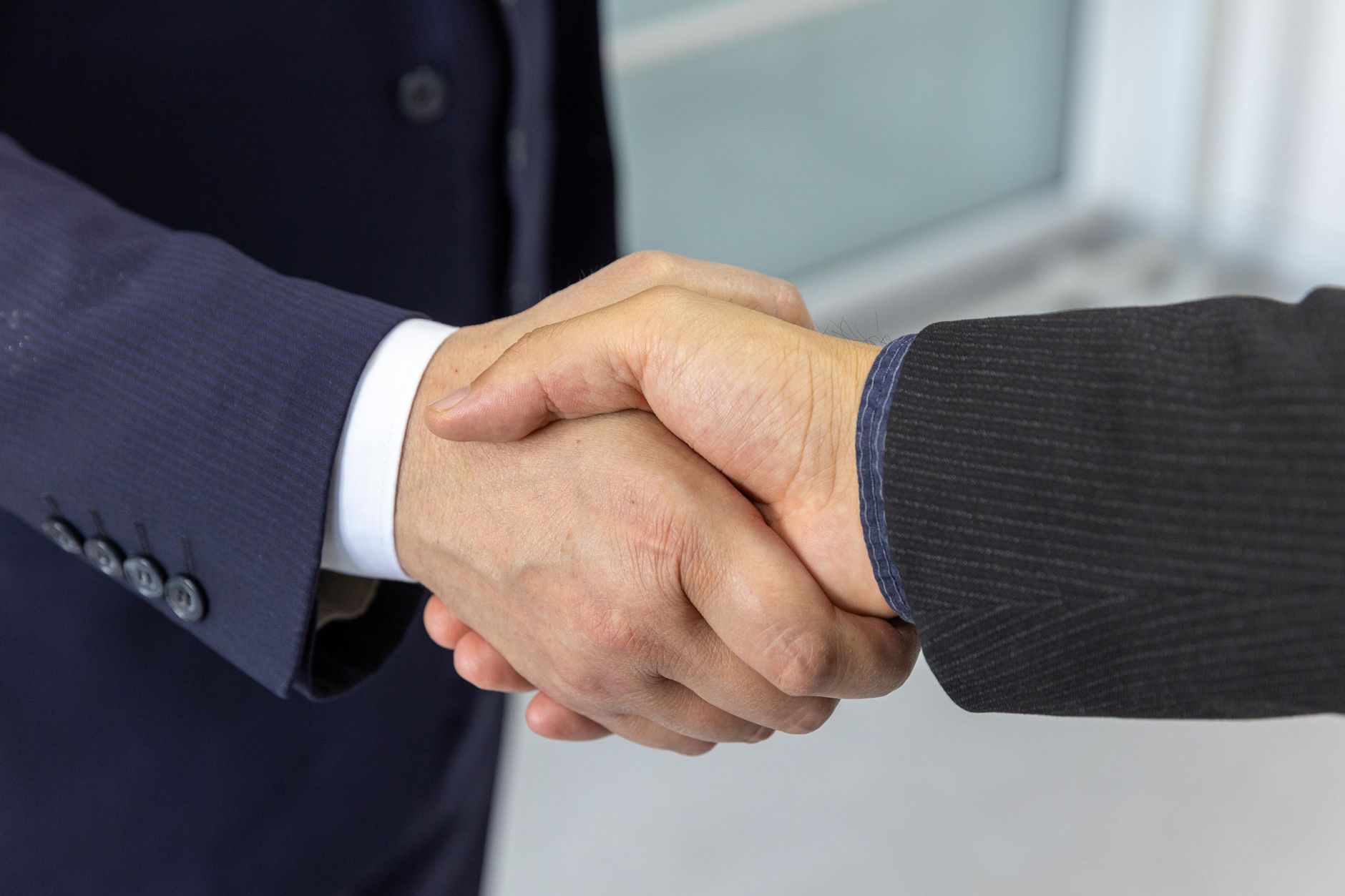 Close-up of two business professionals shaking hands, symbol