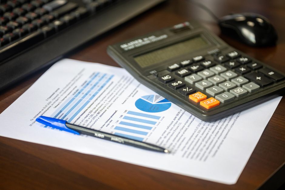 Desk with calculator, financial report, and pen, suggesting
