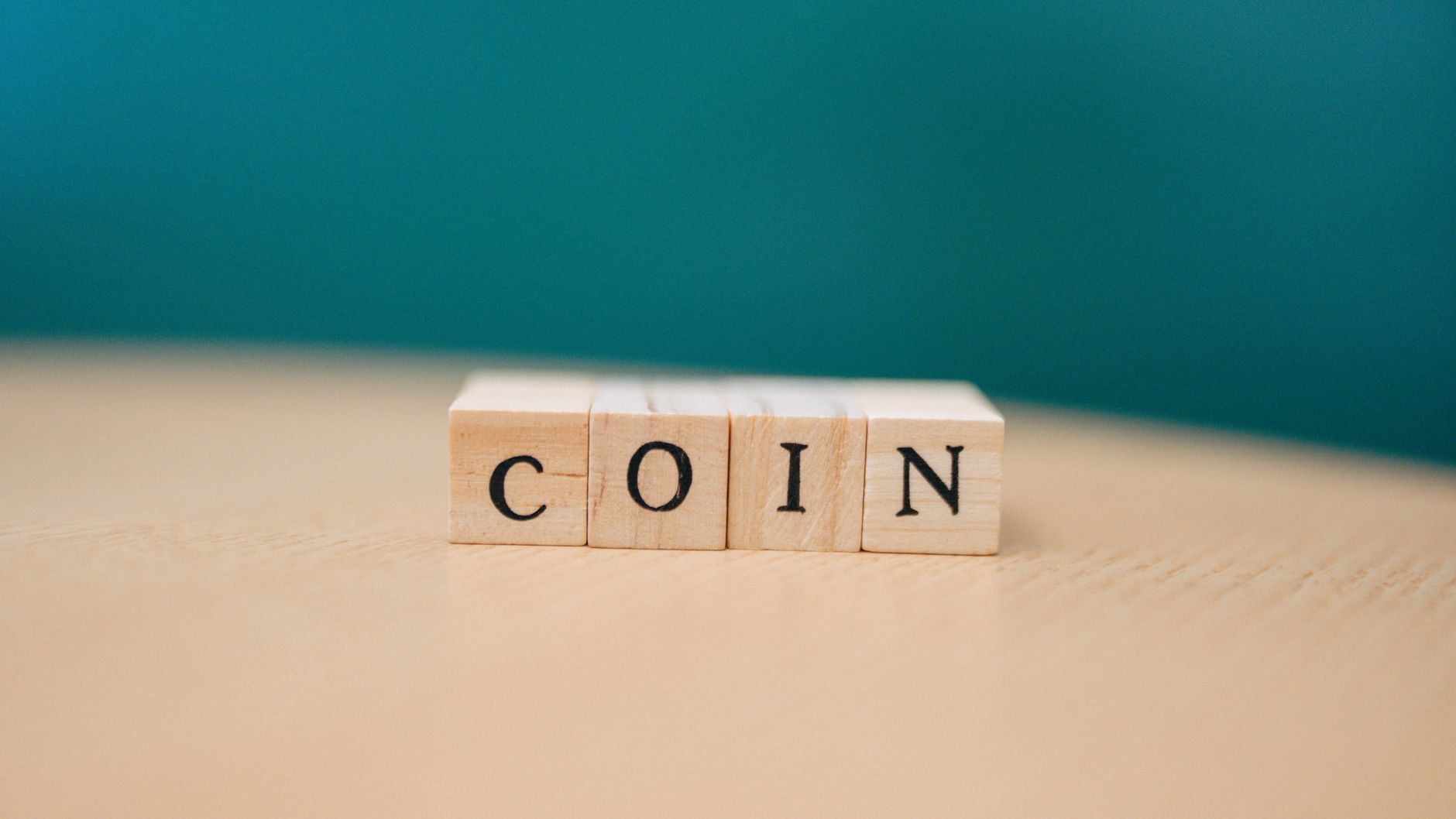 Close-up of wooden blocks spelling 'COIN' on a wooden table